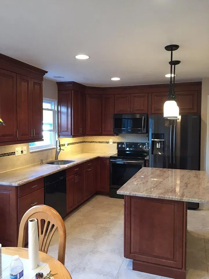 Kitchen with cherry wood cabinets, granite countertops, and black appliances.
