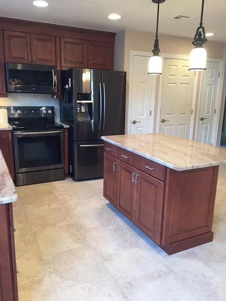 Kitchen with dark brown cabinets, black appliances, light-colored countertops, and island.
