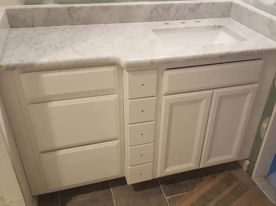 White bathroom vanity with marble countertop and a sink.