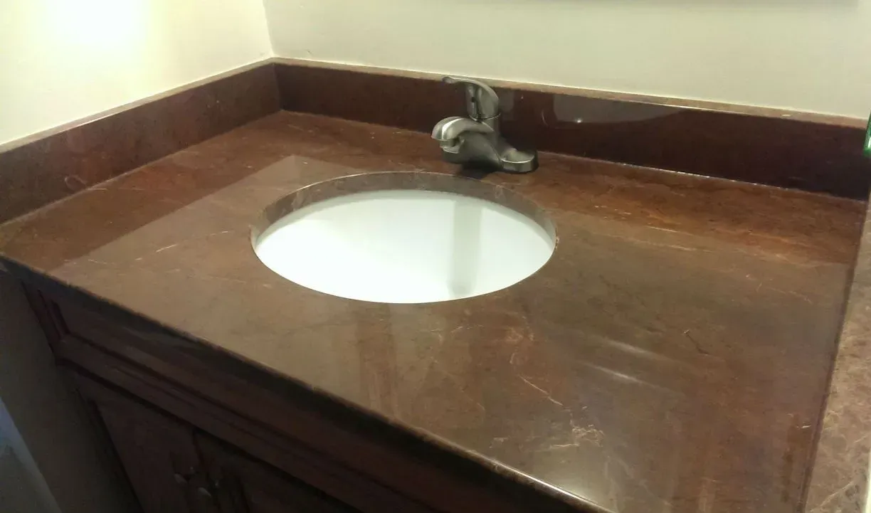 Bathroom vanity with a brown countertop, a white sink, and a silver faucet.