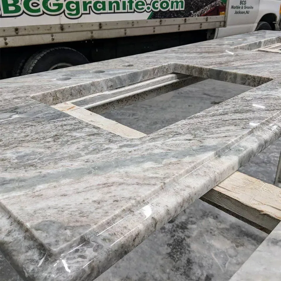 Granite countertop with sink cutout, gray and white swirls, next to a truck.