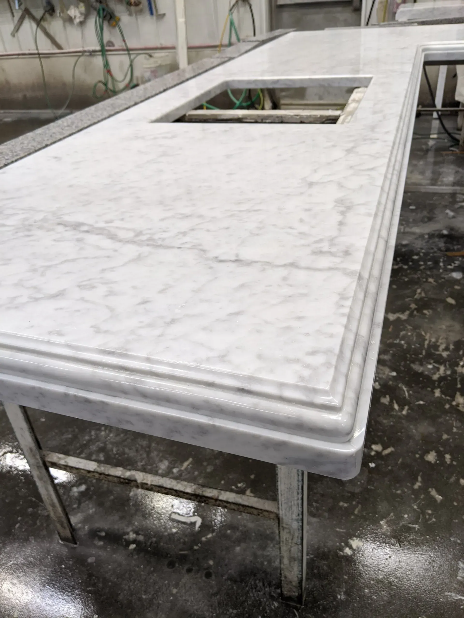 White marble countertop with sink cutout, sitting on metal supports, indoors.