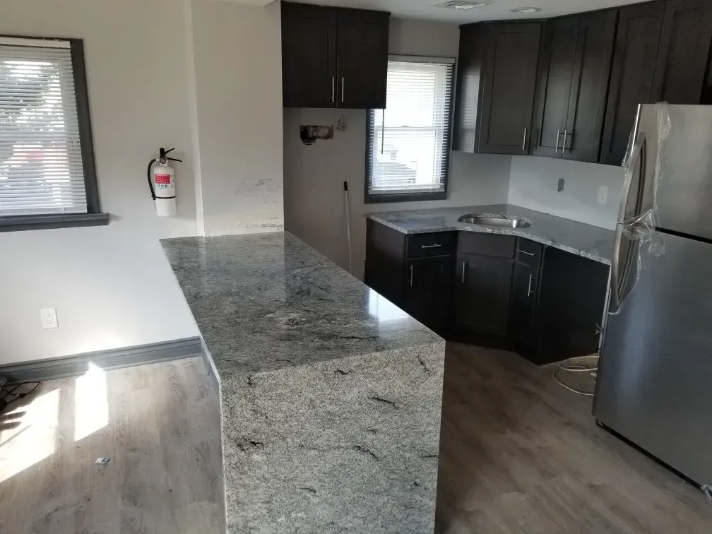 Kitchen with dark cabinets, granite countertops, stainless steel refrigerator, and a breakfast bar.
