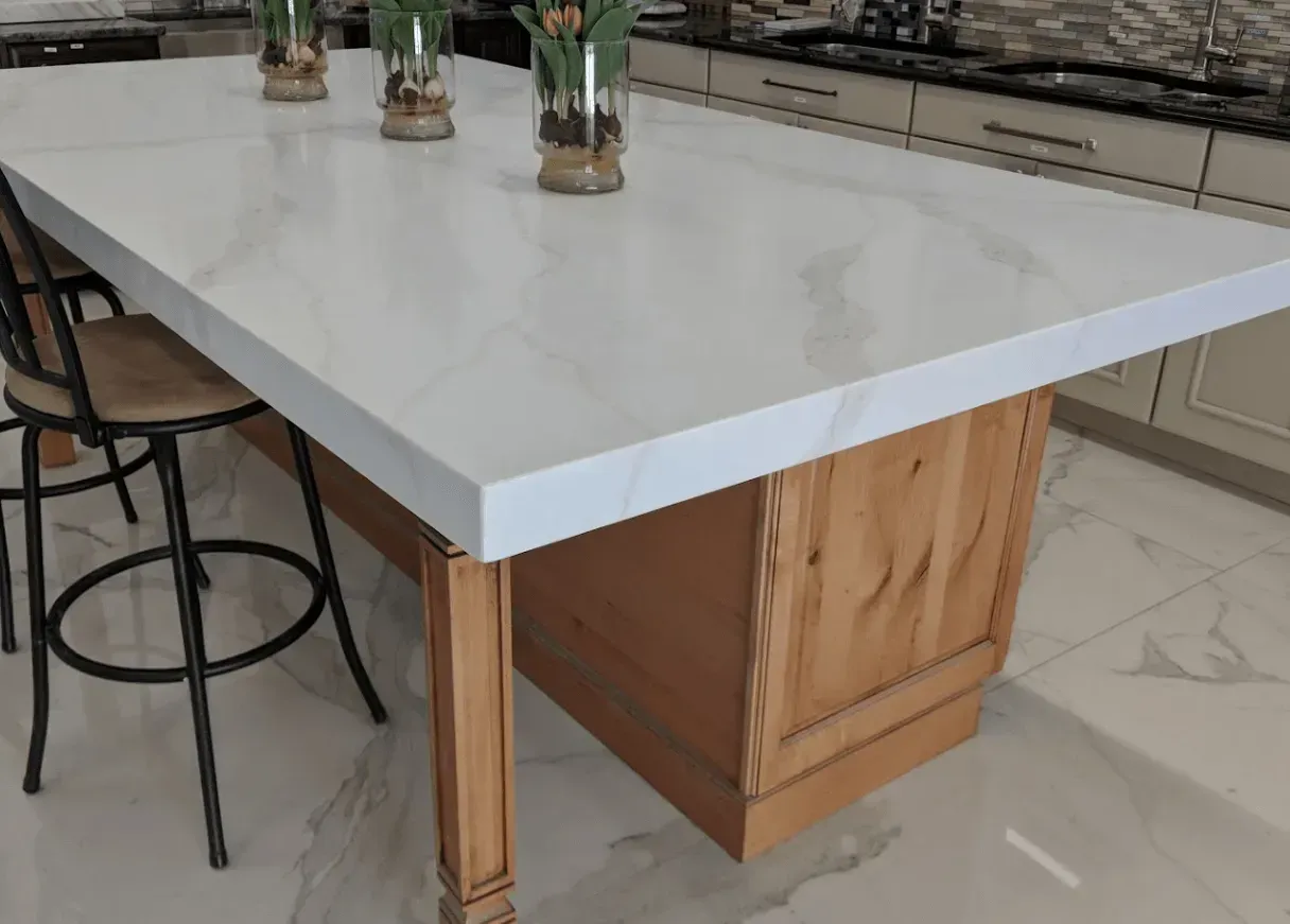 Kitchen island with white countertop, wooden base, and bar stools.