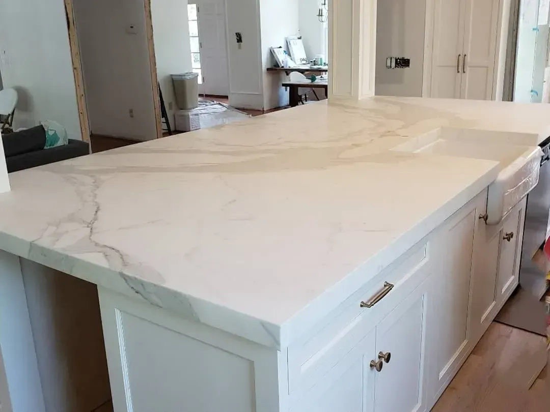 White kitchen island with marble countertop. Cabinets below.