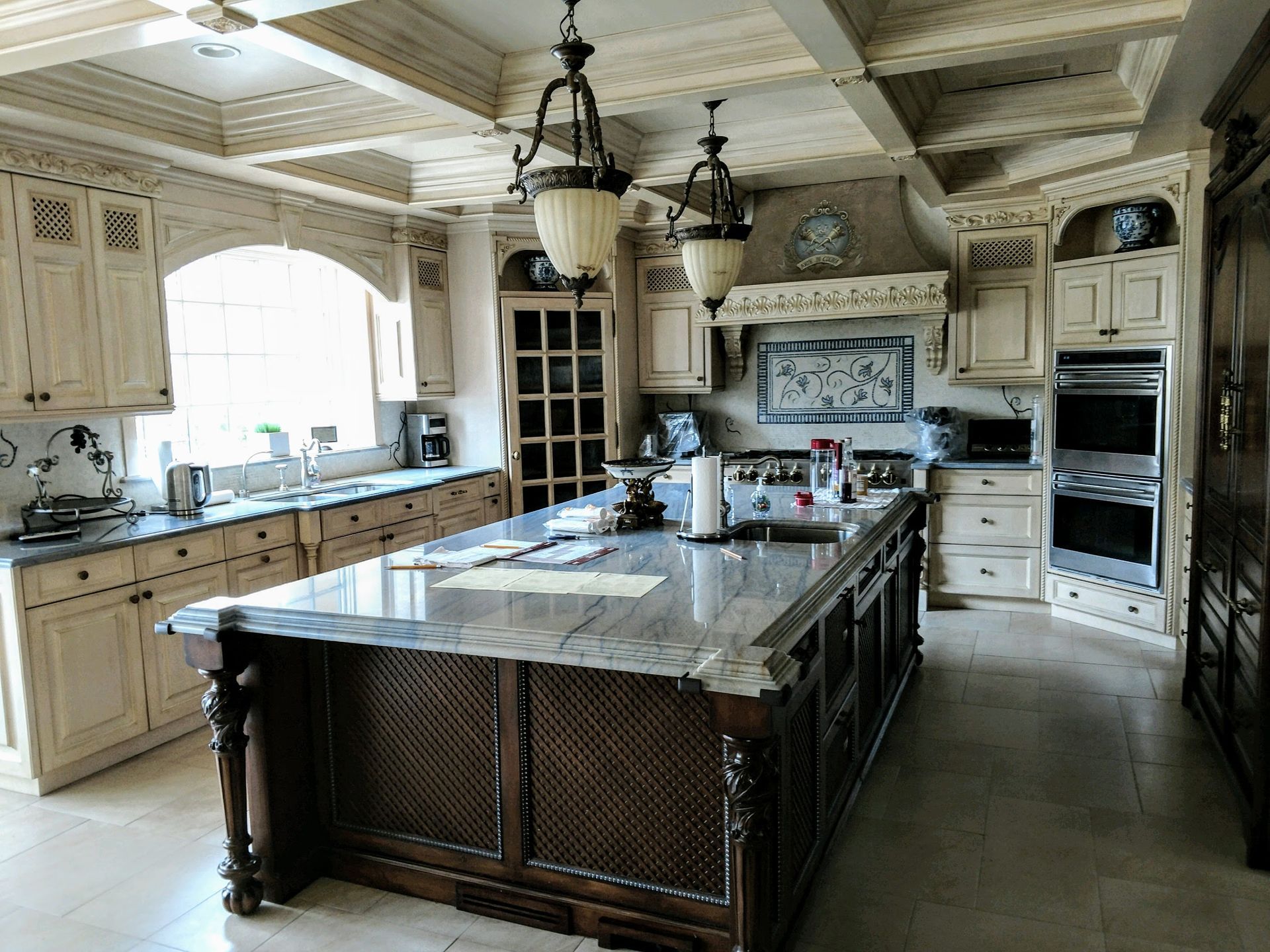 Elegant kitchen with large island, cream cabinetry, granite countertops, and decorative ceiling.