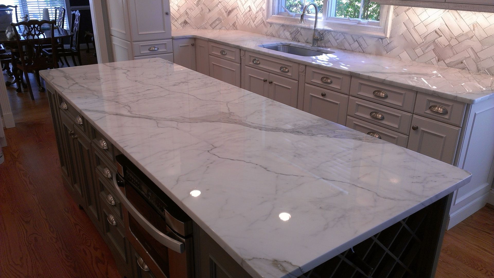 Kitchen with marble countertops and cabinetry; island with oven and wine rack.