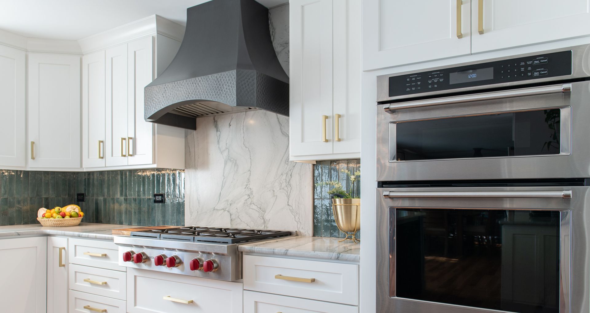 White kitchen with stainless steel appliances, black hood, and gold hardware.