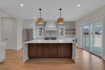 Modern kitchen with a large island, brown cabinets, and two pendant lights.