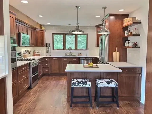 Kitchen with wood cabinets, stainless steel appliances, and island with two stools.