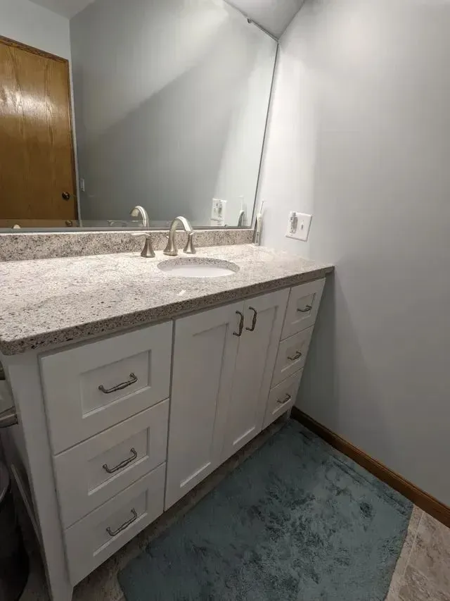 White bathroom vanity with granite countertop, sink, and mirror.