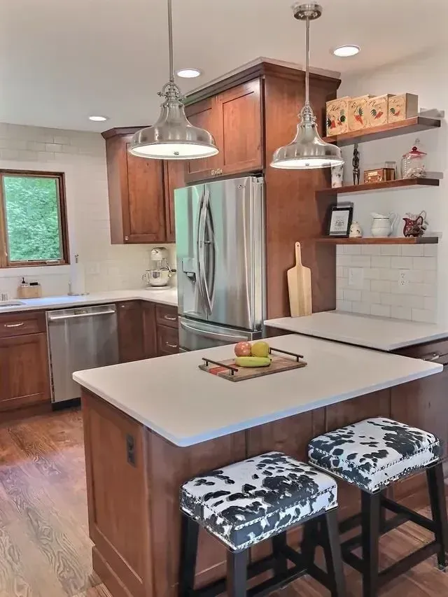 Kitchen with wood cabinets, stainless steel appliances, white countertops, and cowhide stools.