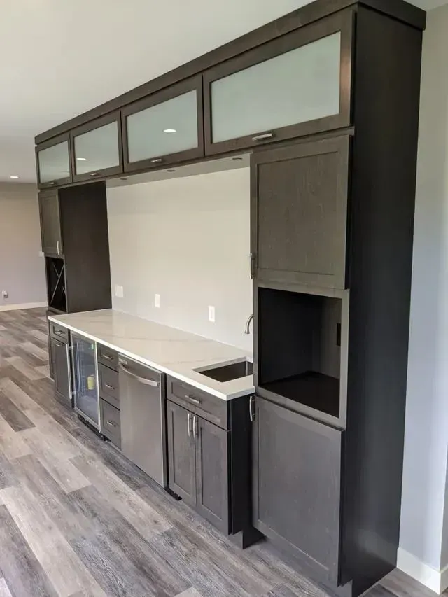 Built-in bar with gray cabinets, a white countertop, and appliances like a mini-fridge and dishwasher.