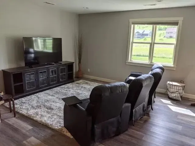 Media room with TV, entertainment console, recliner seating, and window.
