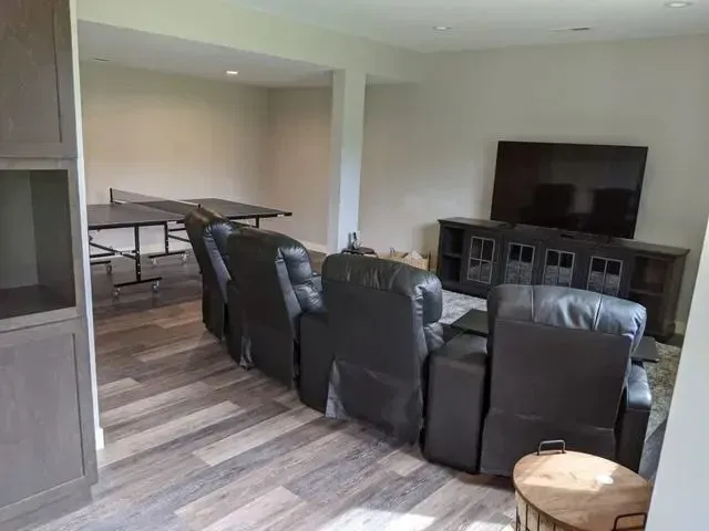 Finished basement with a TV, recliner chairs, and a ping pong table.