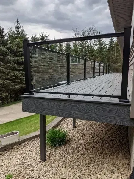 Deck with black railing and gray decking, overlooking a gravel yard.