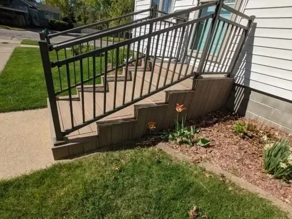 Exterior staircase with black metal railing, leading to a house entrance.