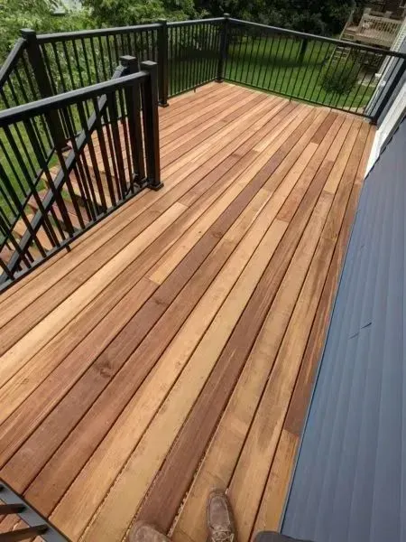 Wooden deck with black railing and stairs leading to grass.