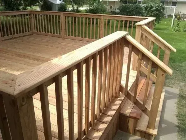 Wooden deck with railings and steps, outdoors.