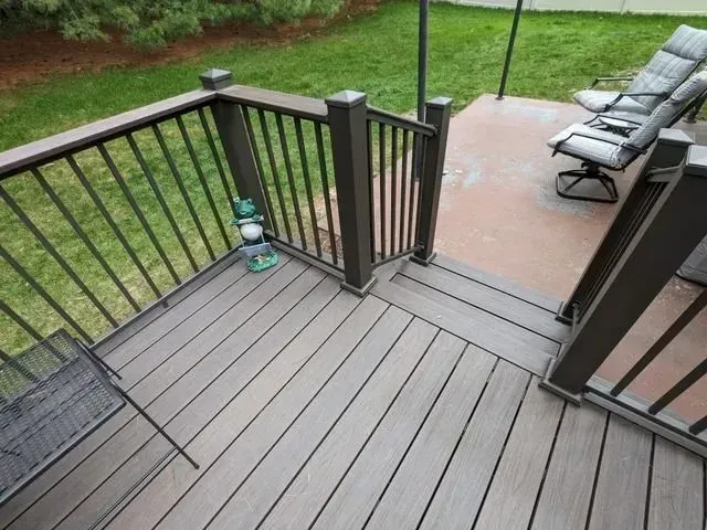 Wooden deck with railing, leading to a grassy yard. Brown and gray tones.