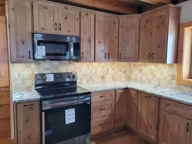 Kitchen with light-colored wooden cabinets, stainless steel appliances, and a tiled backsplash.