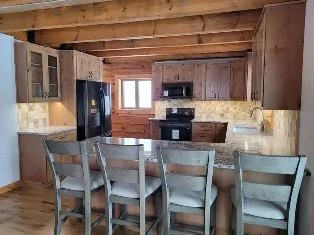 Rustic kitchen with wood cabinets, granite countertops, and breakfast bar with stools.