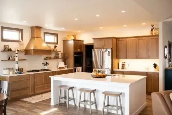 Spacious kitchen with wood cabinets, white island, stainless steel appliances, and wood floor.