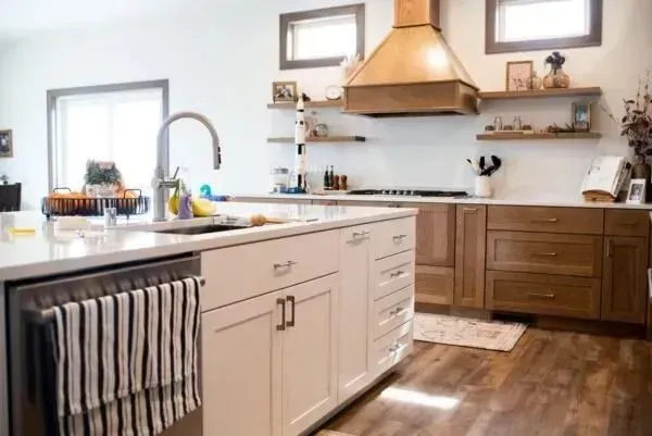 Kitchen with white island, wood cabinets, range hood, open shelves, and wood floors.