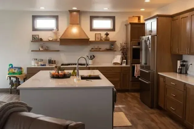 Modern kitchen with wooden cabinets, island, stainless steel appliances, and floating shelves.
