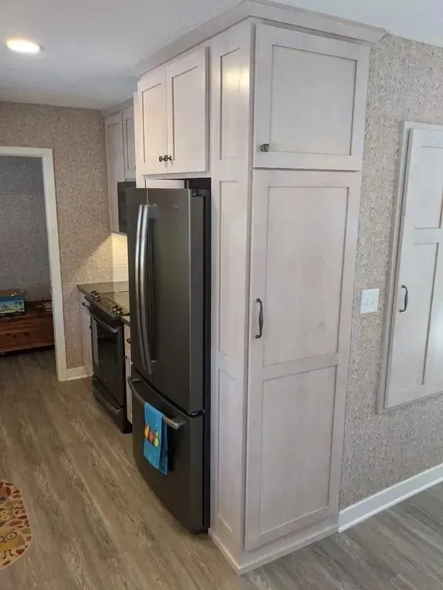 Kitchen with light grey cabinets, stainless steel refrigerator, and wood-look flooring.