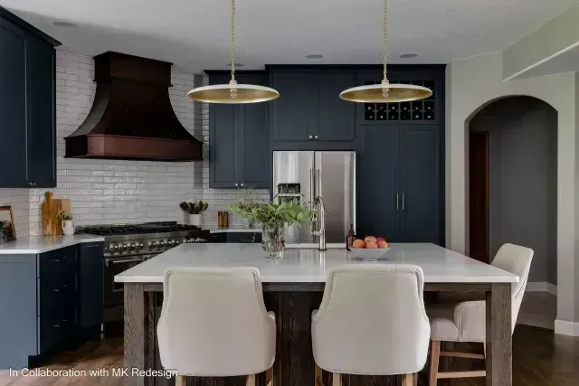 Modern kitchen with dark blue cabinets, white countertops, and a wooden island.