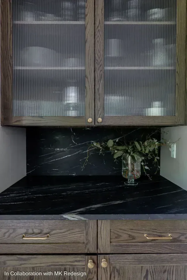 Kitchen cabinets with ribbed glass doors and a dark countertop.