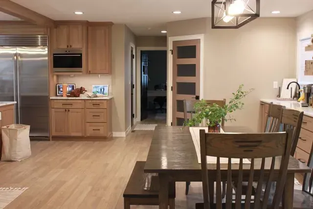 Kitchen with wooden cabinets, stainless steel appliances, and a dining table with chairs.