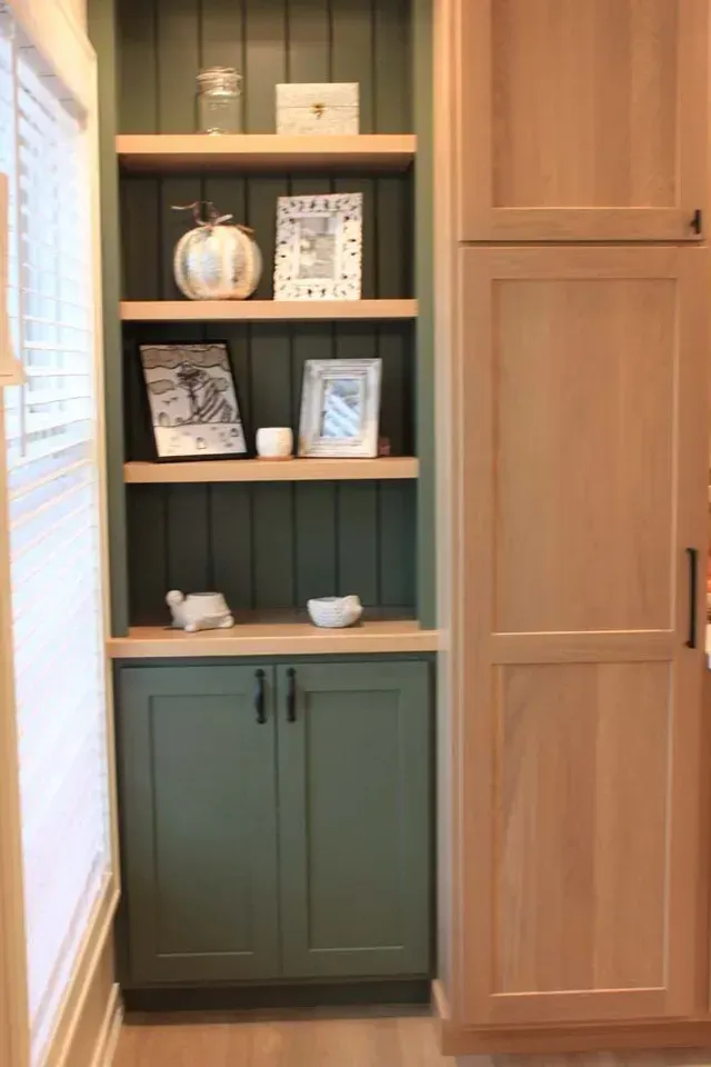 Built-in kitchen storage: green shelving unit with open shelves, lower cabinets, and natural wood trim.