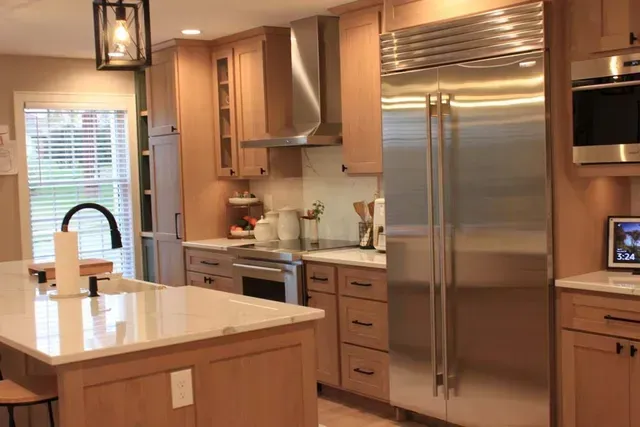 Modern kitchen with light wood cabinets, stainless steel appliances, and a large island.