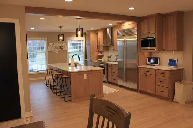 Kitchen with wood cabinets, island with stools, and stainless steel appliances.