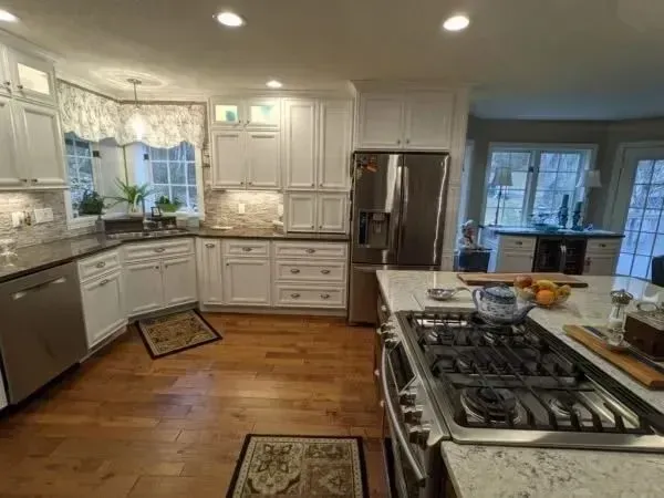 Spacious kitchen with white cabinets, stainless steel appliances, and hardwood floors.