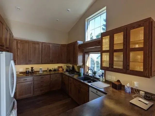 Kitchen with wood cabinets, countertop, and appliances. Sunlight streams through a window.