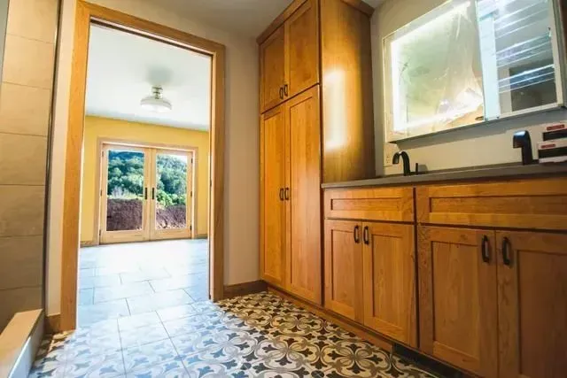 Bathroom with wooden cabinets and patterned floor, doorway to another room with French doors.