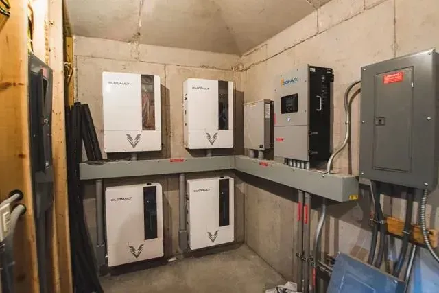 Solar panel and electrical equipment installed on a concrete wall in an indoor setting.