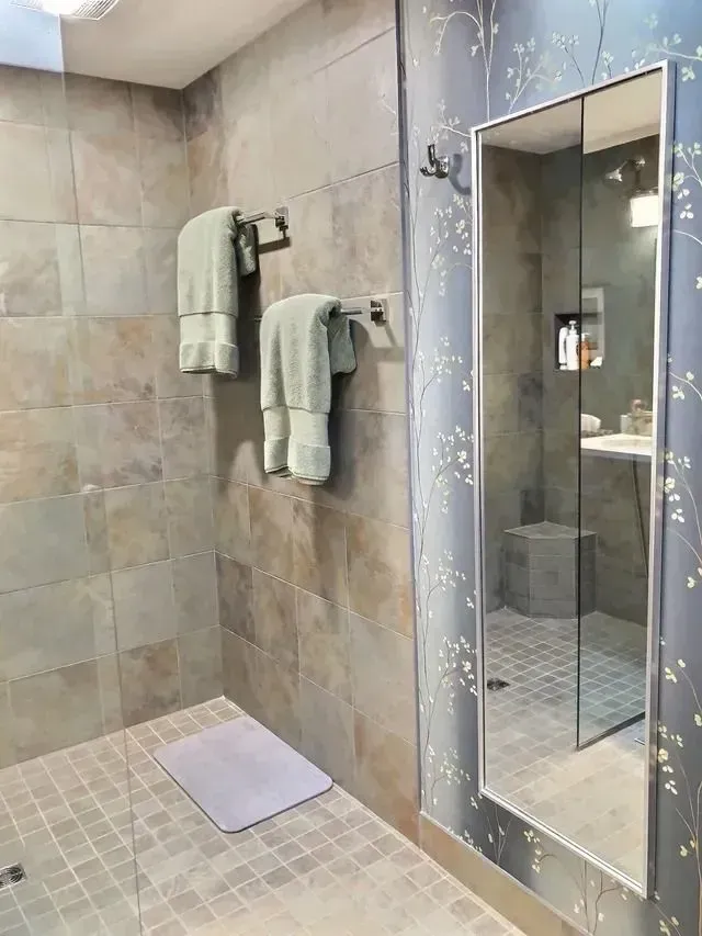 Bathroom with tiled walls, towels on a rack, and a mirrored cabinet.
