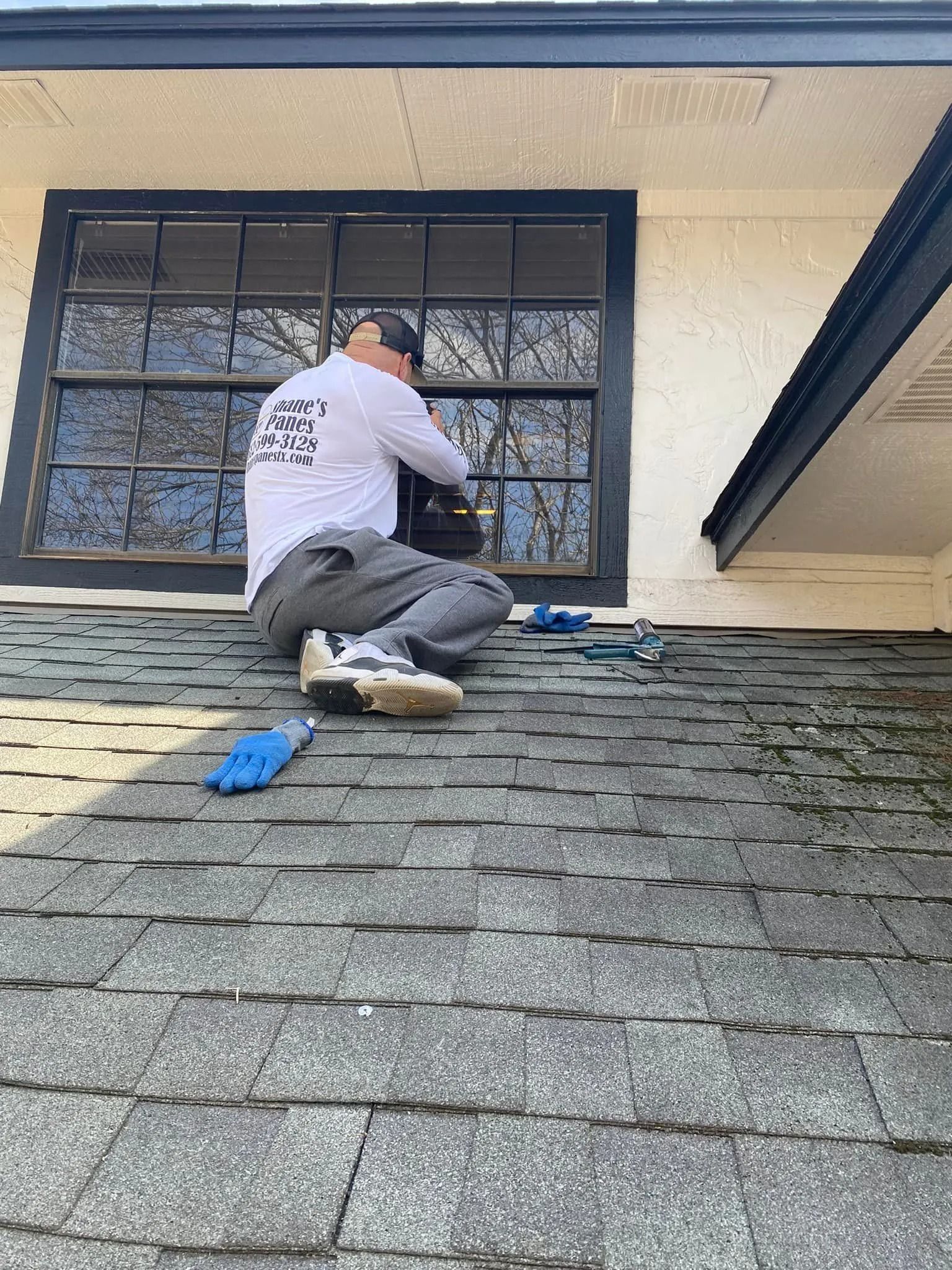 Person on a roof working near a window, tools nearby.