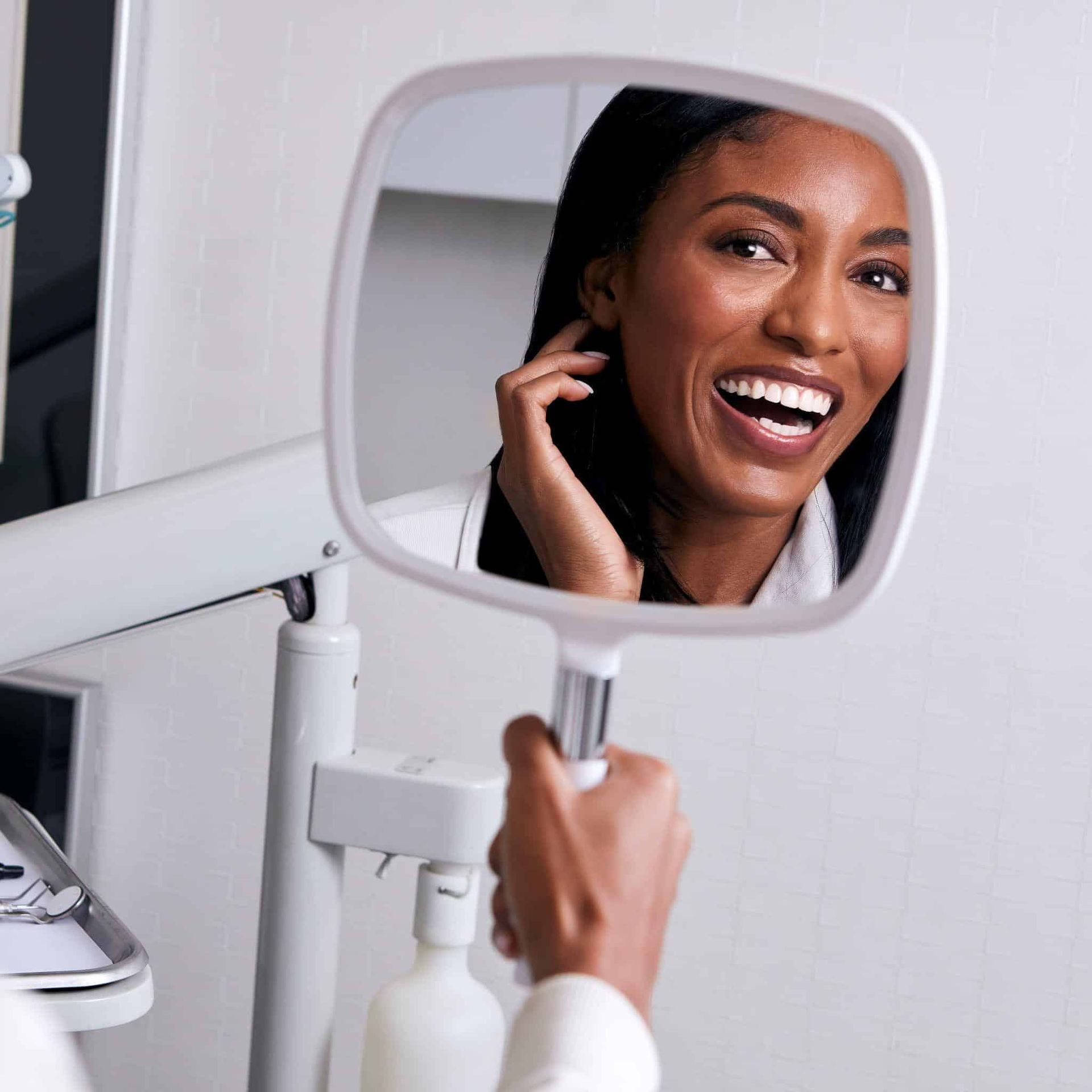 A woman is smiling while looking at herself in a mirror