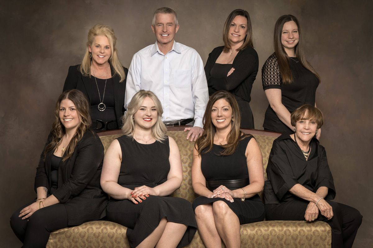 A group of people are posing for a picture while sitting on a couch.