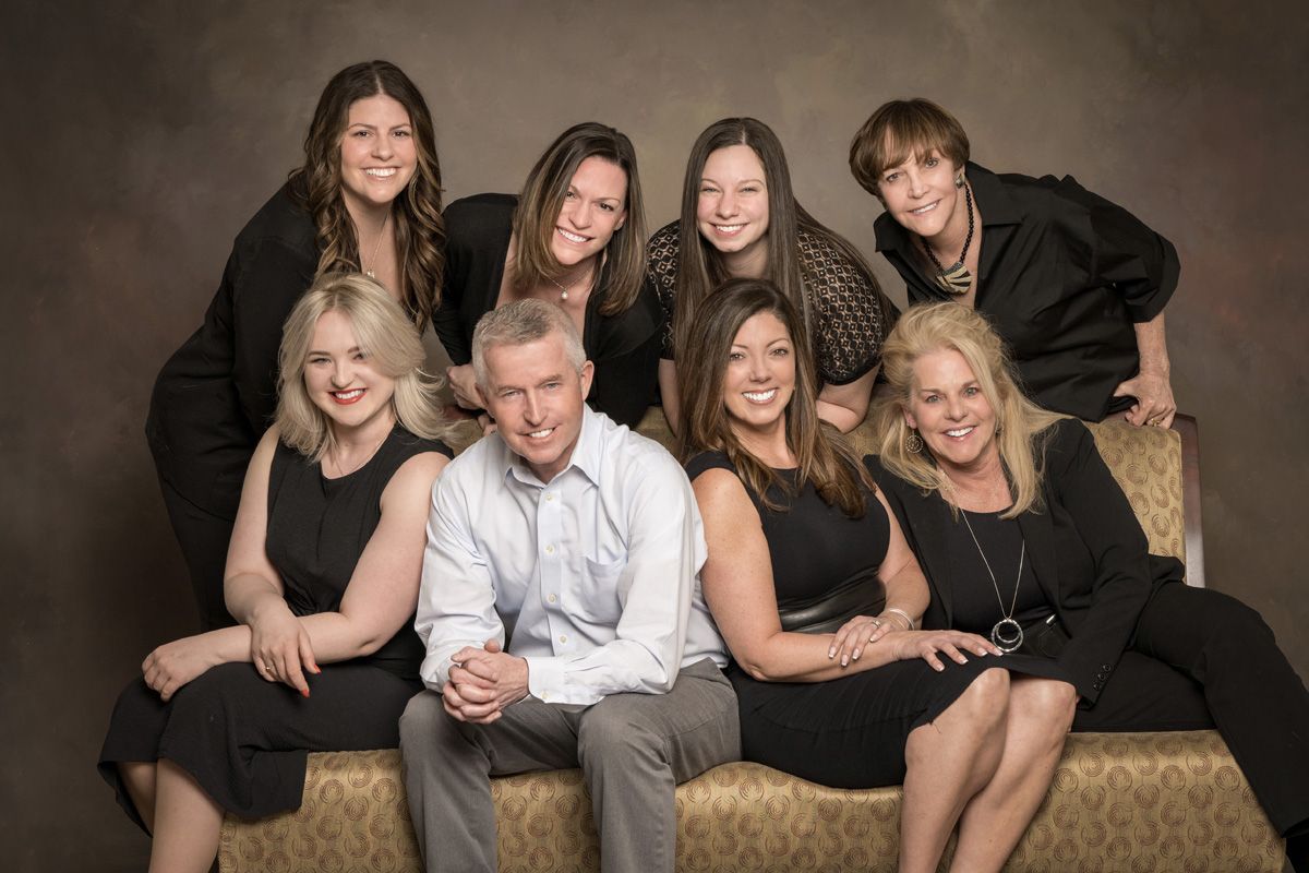 A group of people are posing for a picture while sitting on a couch.