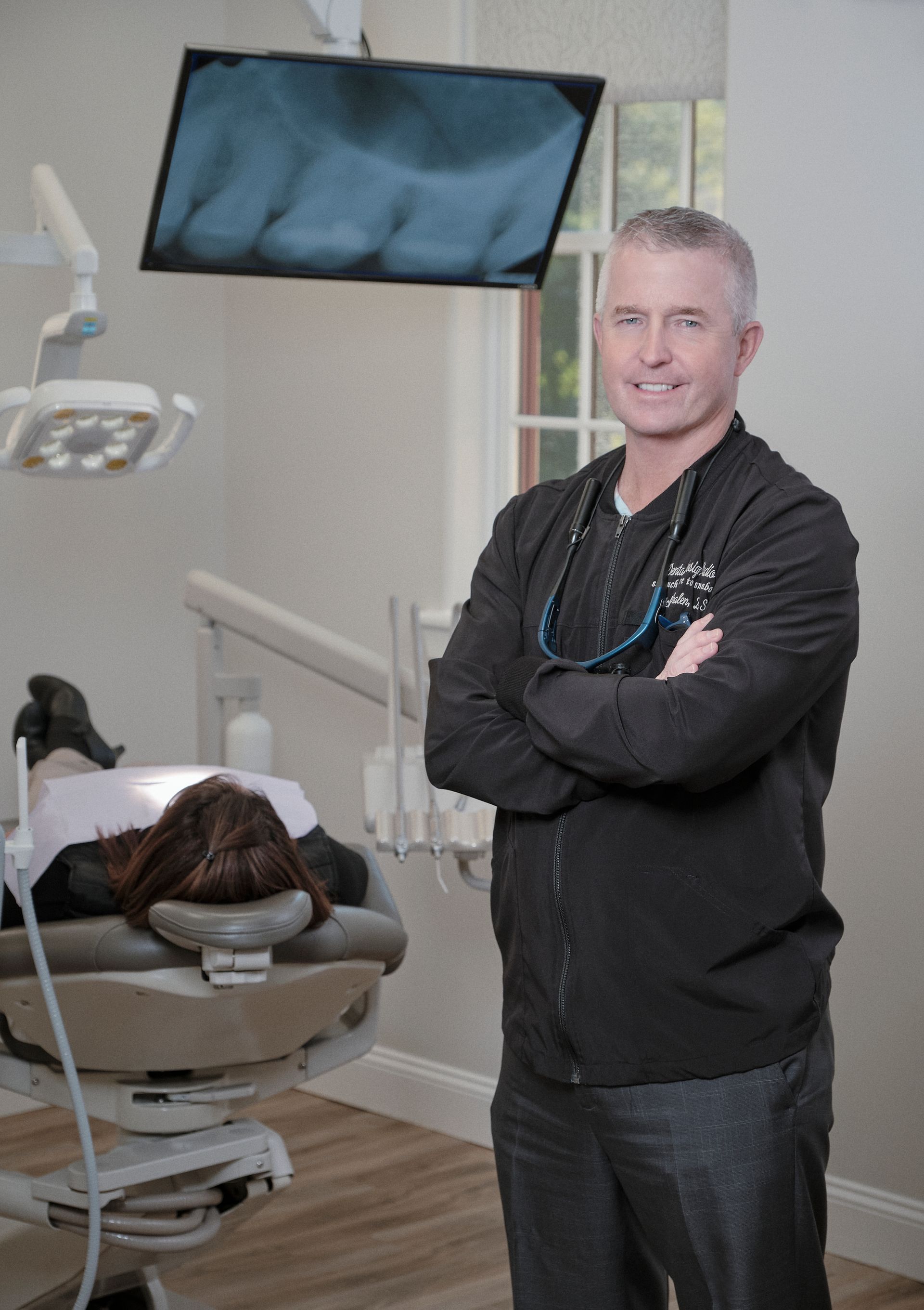 A dentist is standing in front of a patient in a dental chair.
