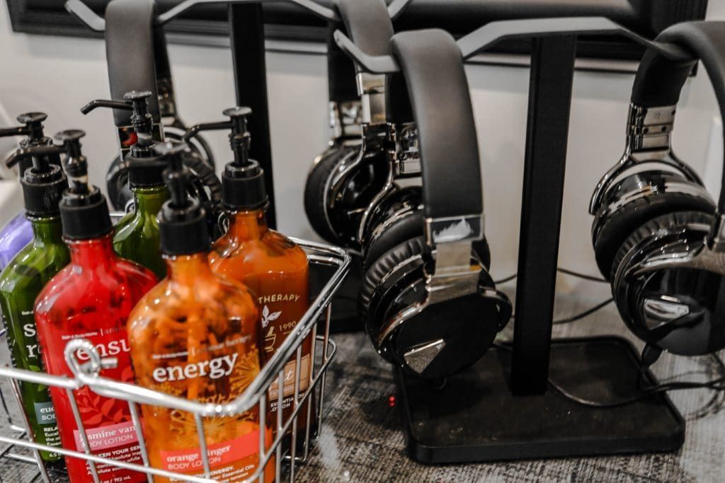A bunch of headphones are sitting on a table next to a basket of energy drinks.