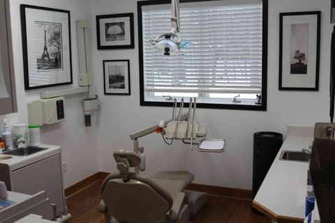 A dental office with a dental chair and a sink.