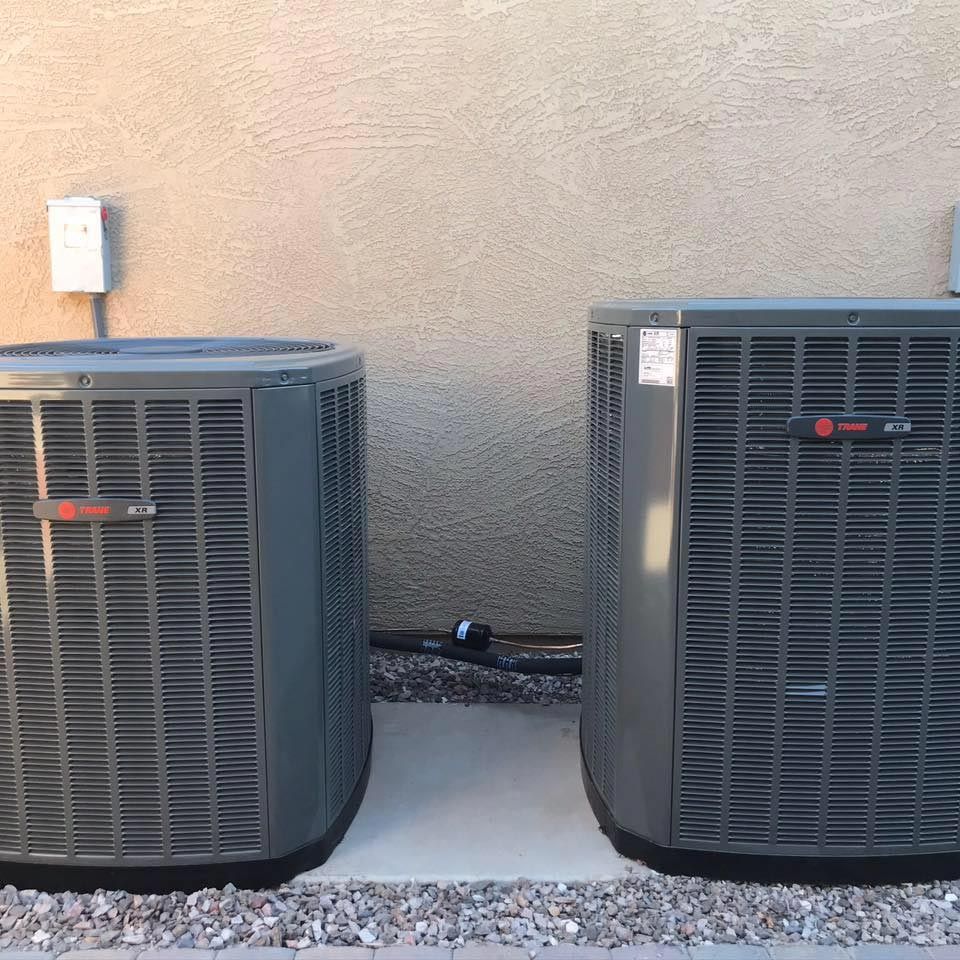 Two air conditioners are sitting next to each other on the side of a building.