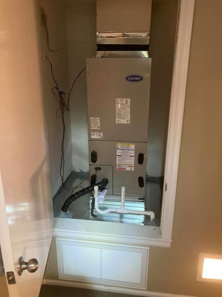 An air conditioner is sitting in a closet next to a door.